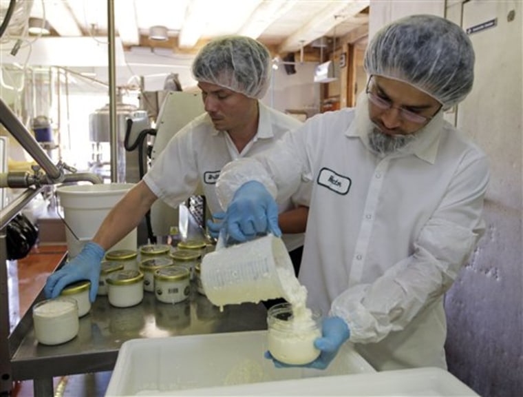 In this June 25, 2012 photo, Hector Flores, right, and Britton Comer hand pack cottage cheese at Traders Point Creamery in Zionsville, Ind. Traders Point packages it's artisanal cottage cheese in glass jars. (AP Photo/Michael Conroy)